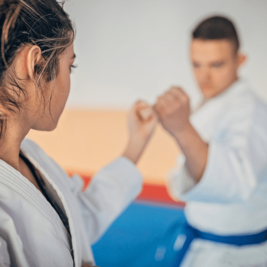 Frau zeigt Karate Abwehrtechnik mit Mann im blauen Gürtel